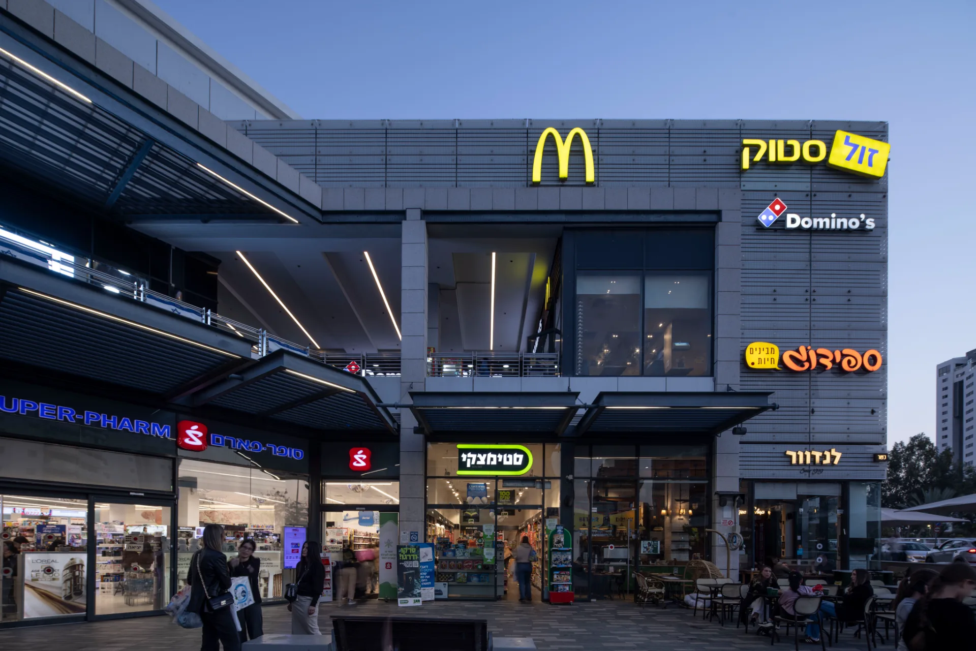 Lit storefronts and signage along the retail frontage at night