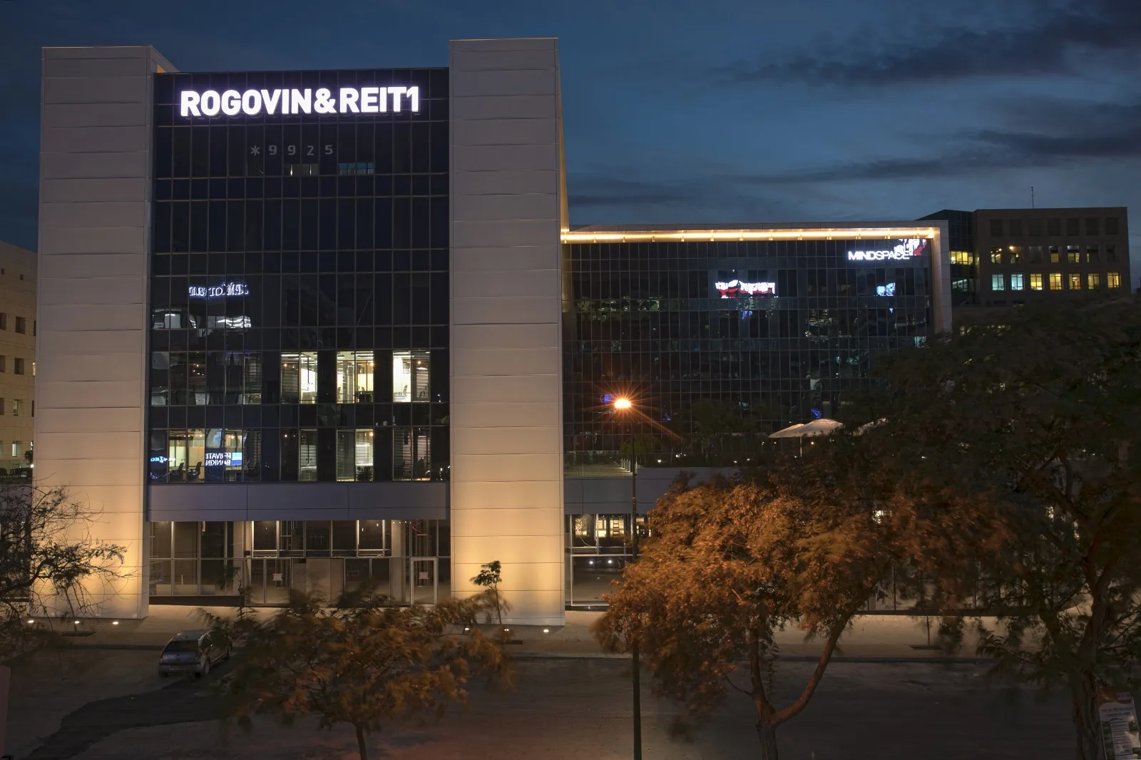 The entrance facade at dusk with lit signage and light-washed stone piers