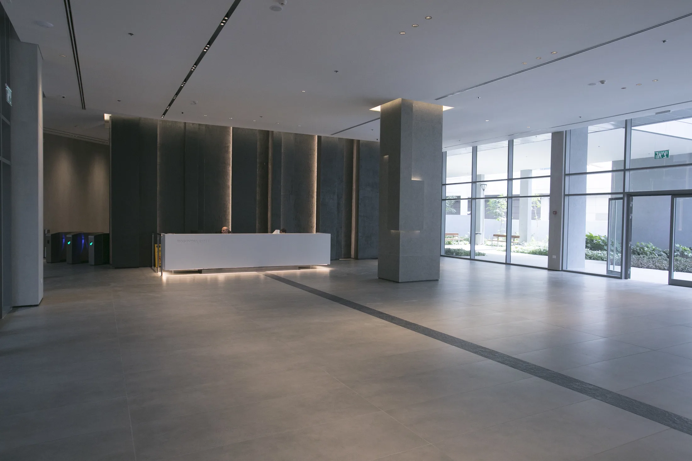 The entrance lobby with an under-lit floating reception desk and a light-washed stone wall