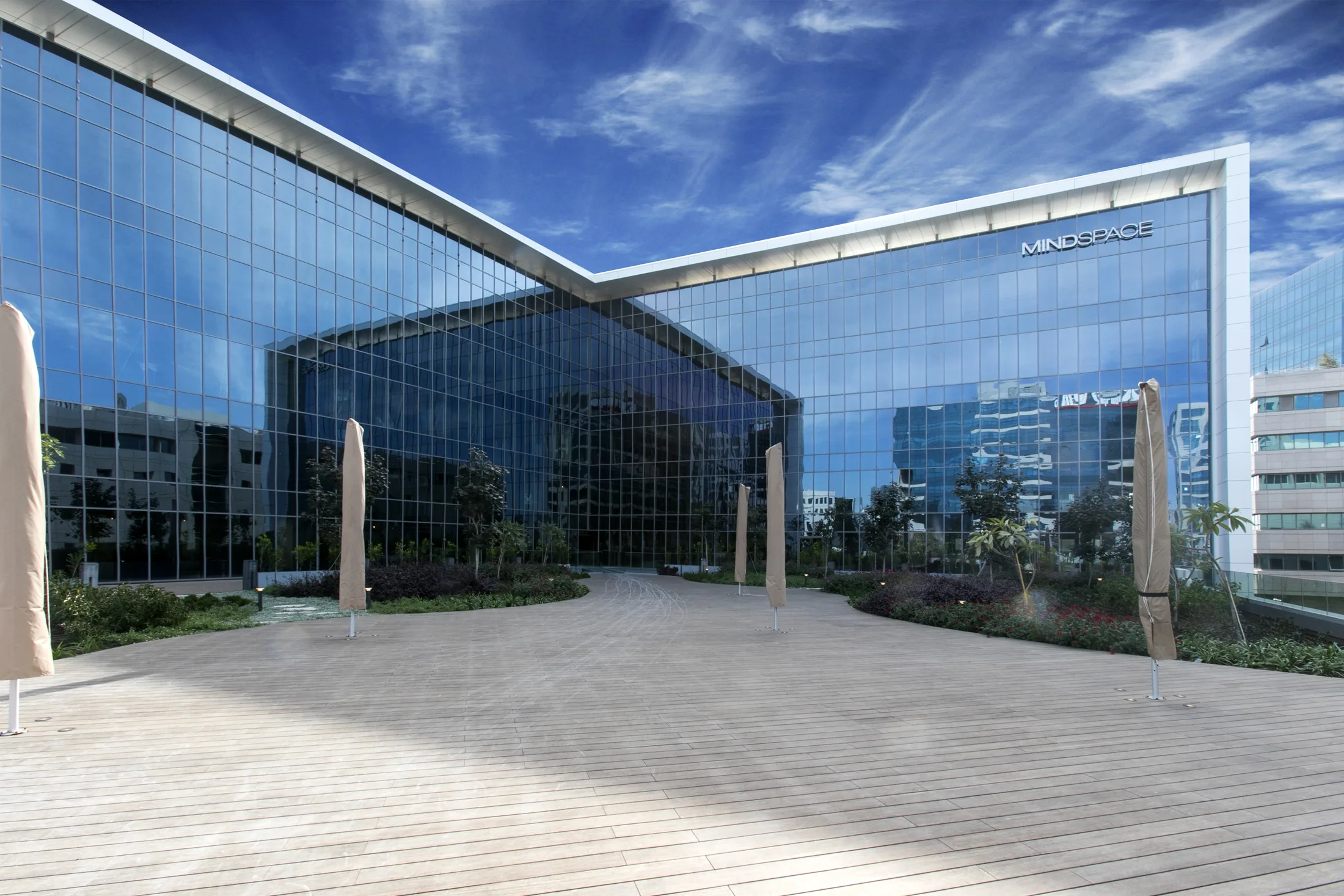 The building's glass corner and courtyard in daylight