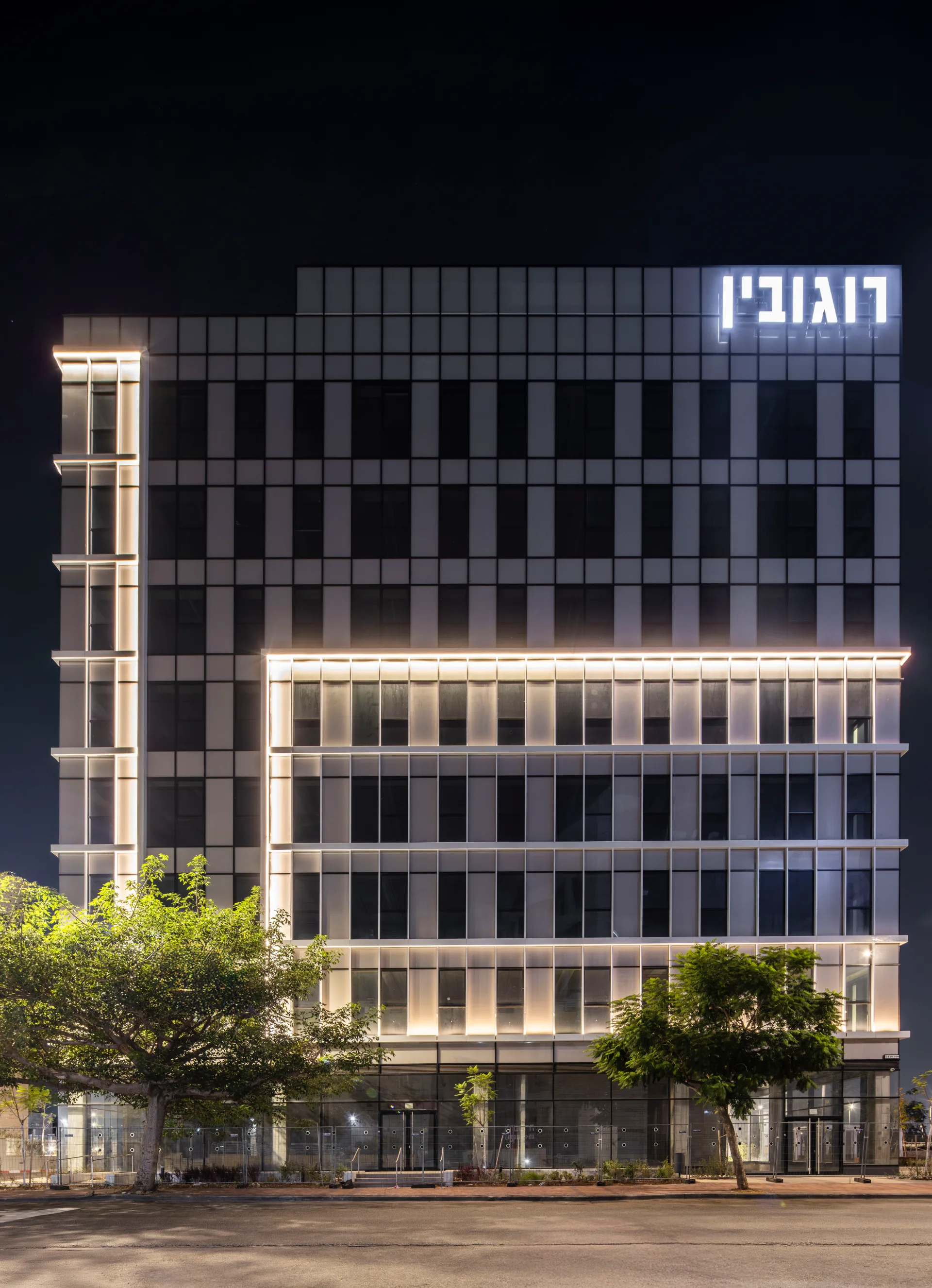 Office tower facade with an illuminated vertical light element at night