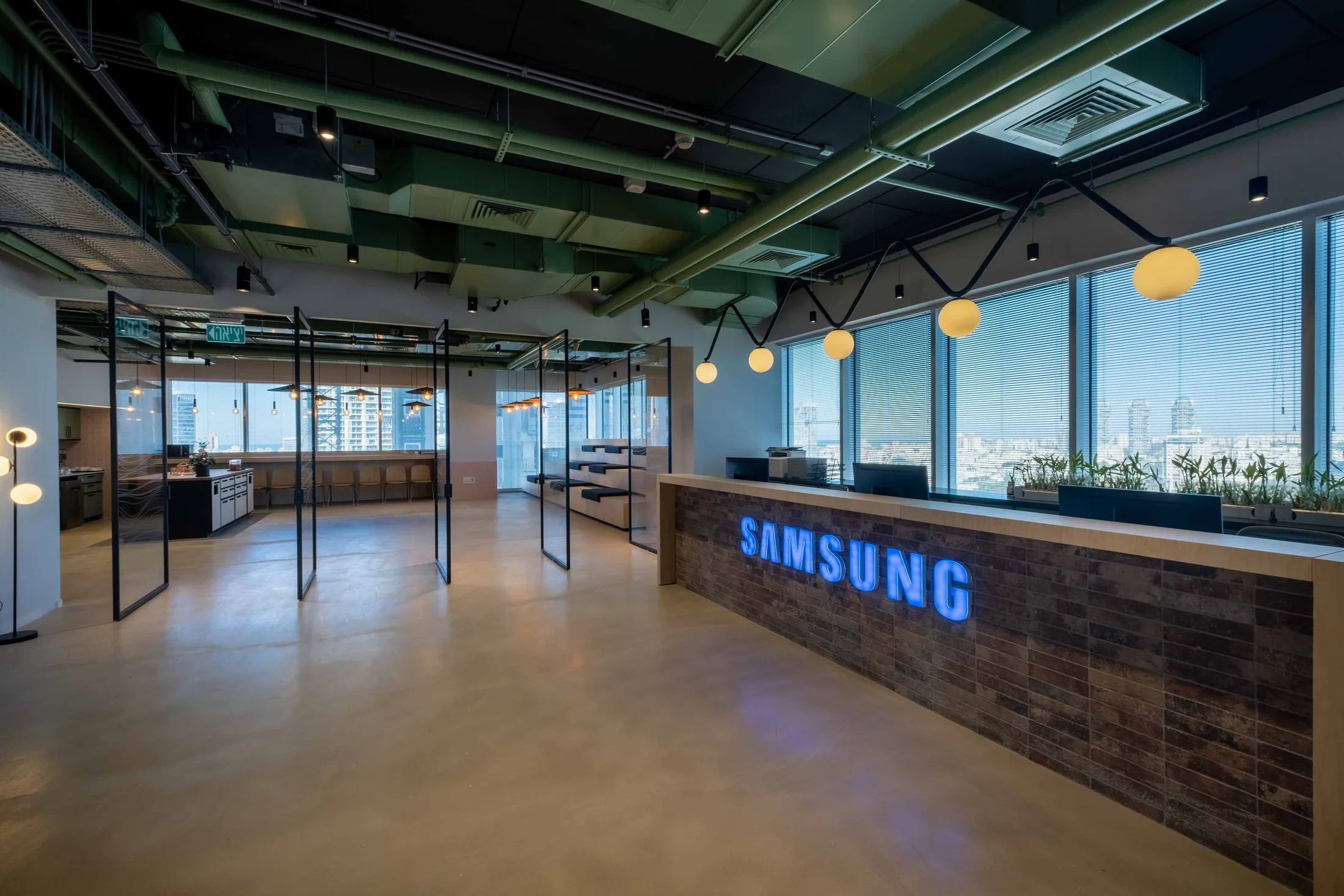The reception area with a lit SAMSUNG logo and zigzag pendant lights over the space