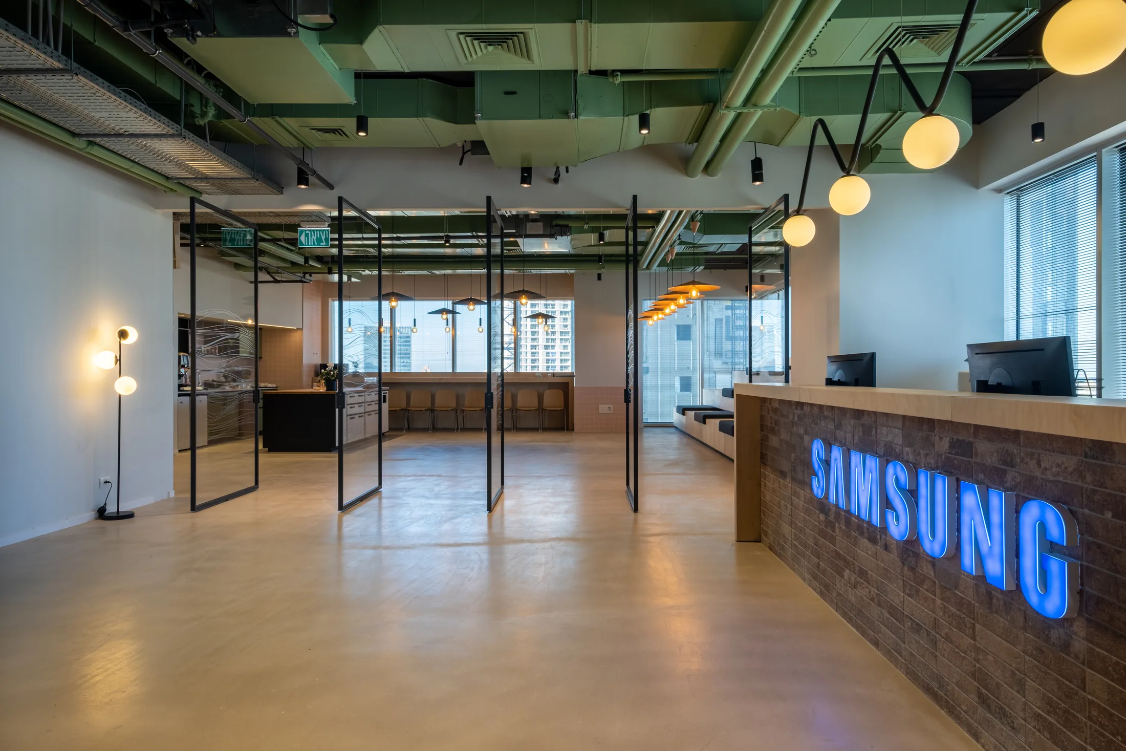 A reception and lounge corner with a branded desk and an exposed services ceiling