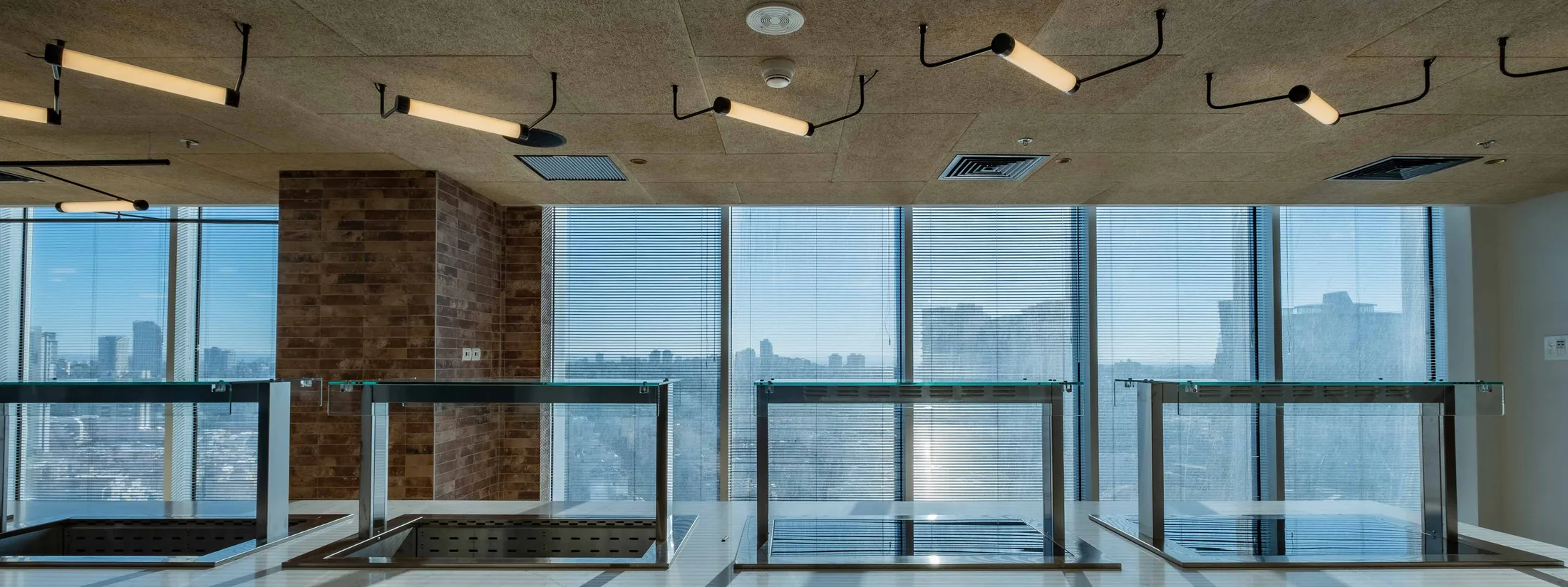 A room with a brick wall and angular track luminaires on the exposed ceiling