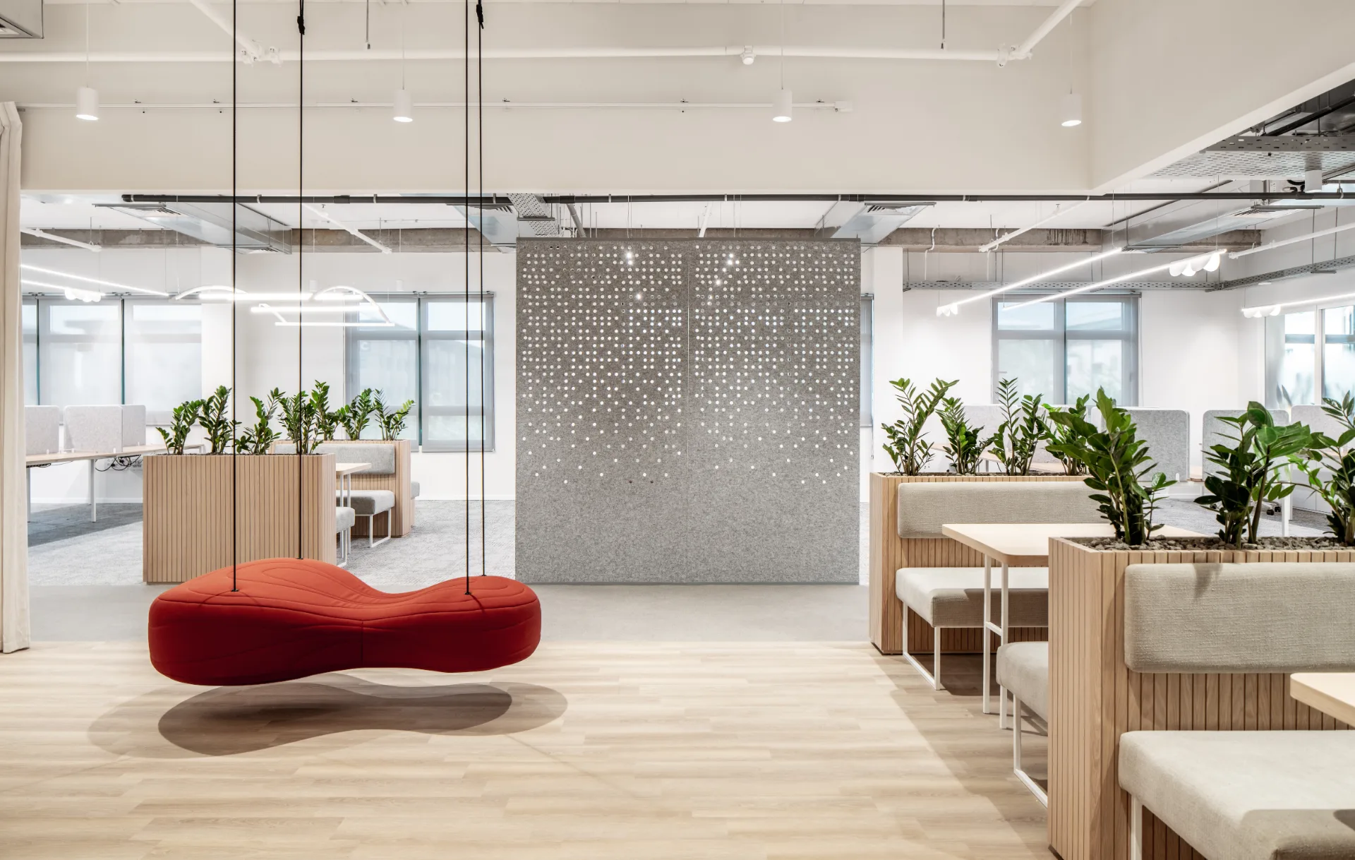 Breakout corner with a red sofa and perforated screens