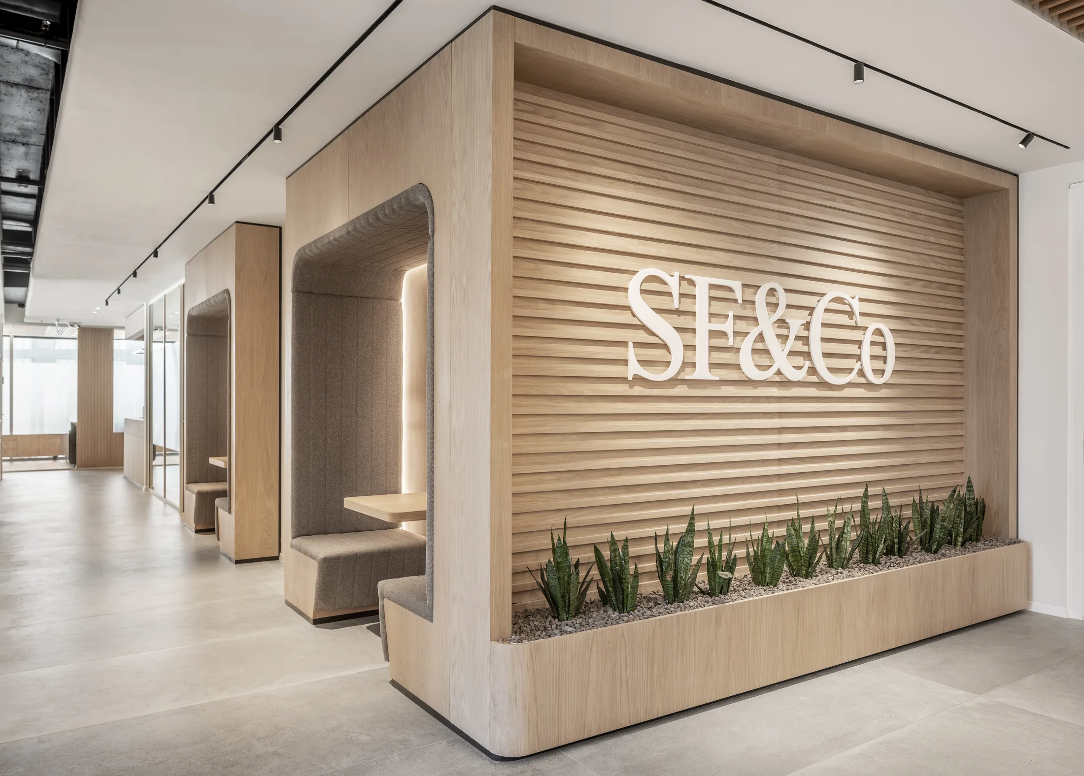 The backlit timber-slat SF&Co branded wall with glowing acoustic seating booths