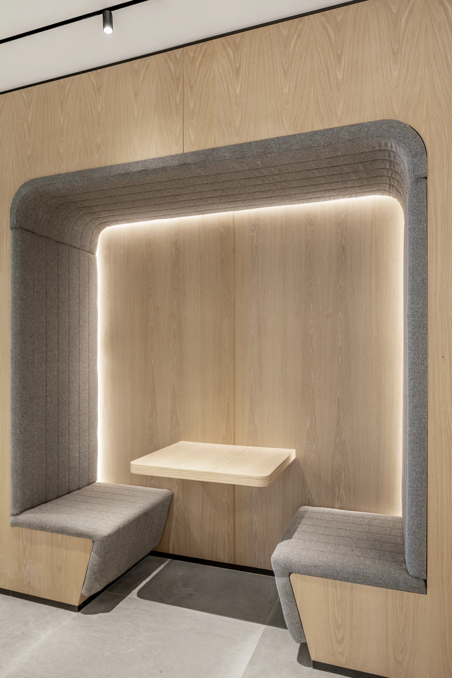 An acoustic seating booth with a concealed warm light halo around the wood back