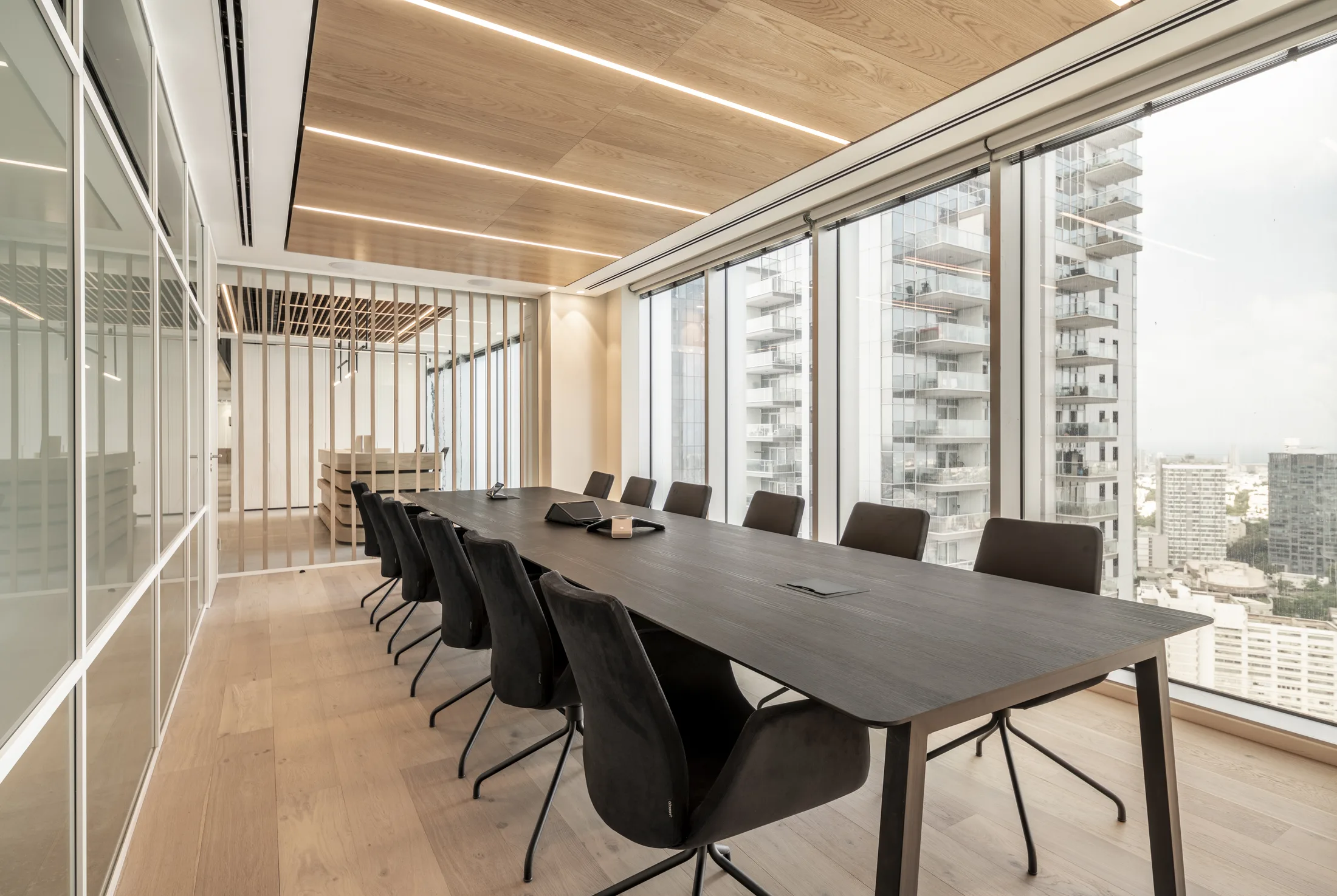 A boardroom with a wood ceiling and perimeter cove lighting facing the skyline
