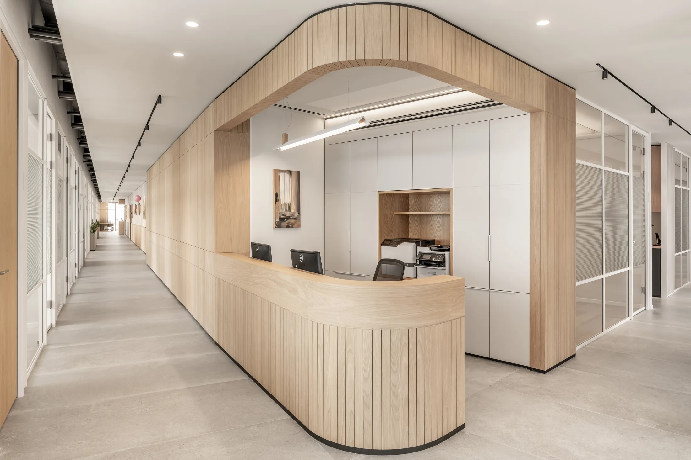 A curved wood-clad secretary station with recessed lighting and track lighting