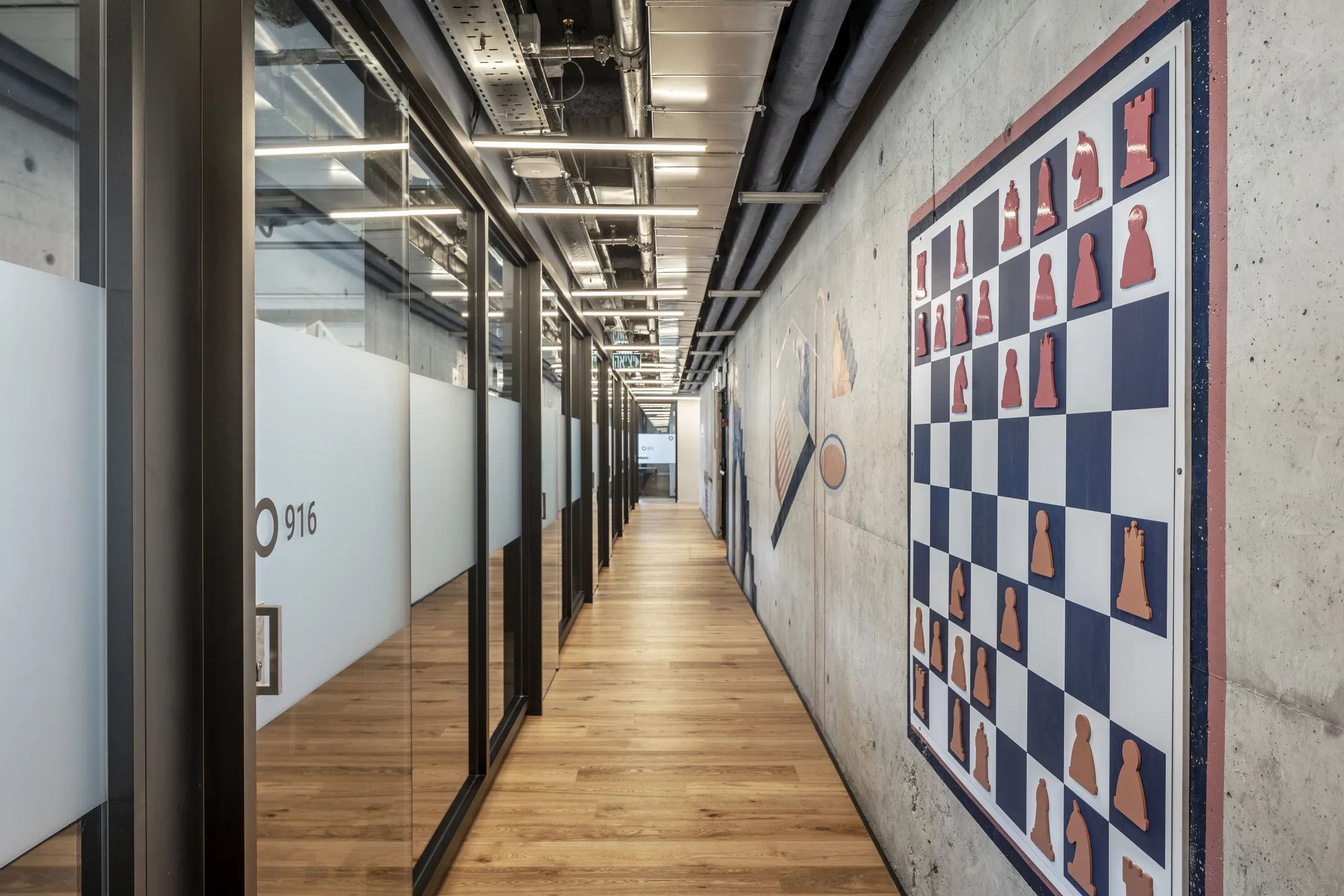 An office corridor with a chess-board mural and glazed offices