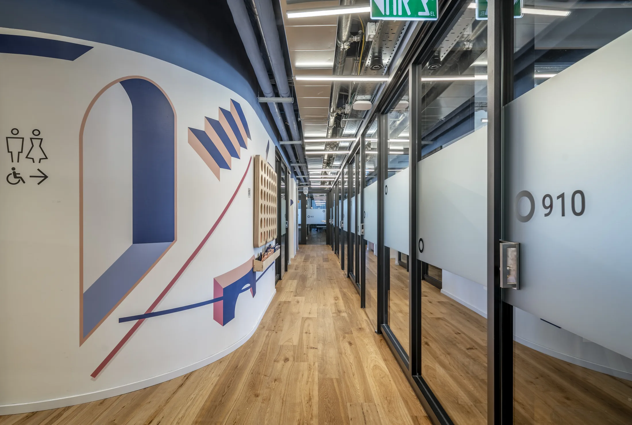 A wayfinding corridor with a graphic mural and glazed offices