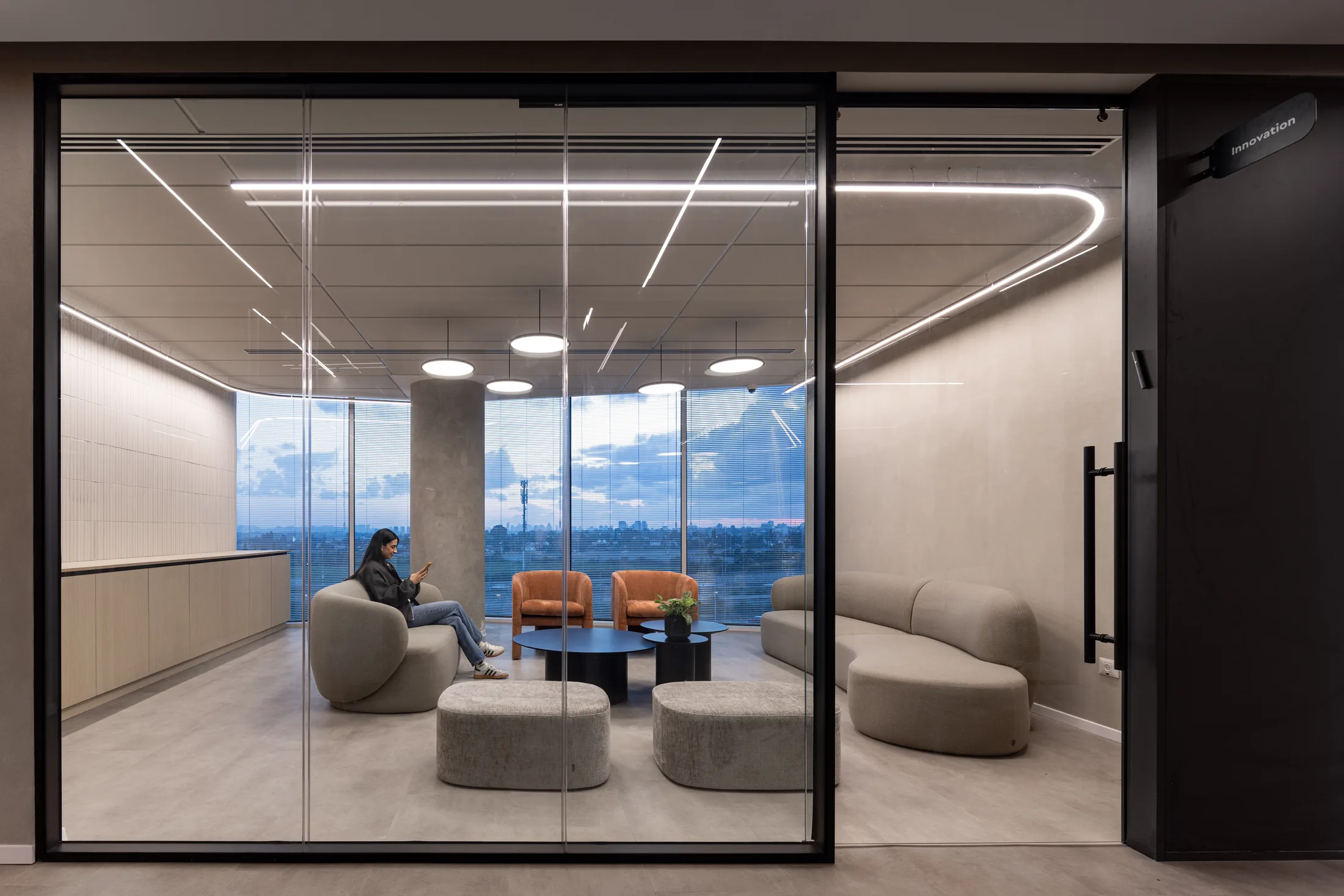 An evening view into a glazed lounge with linear light lines