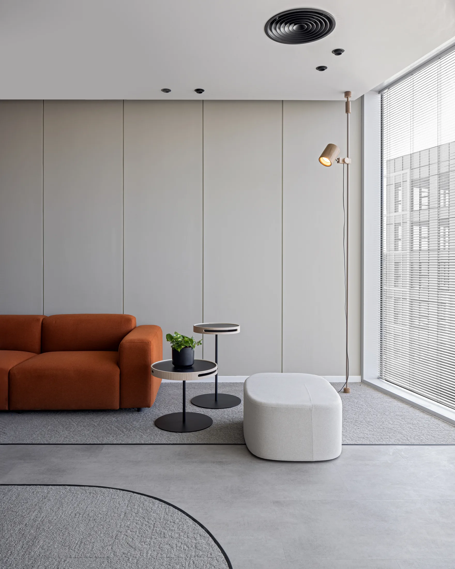 A quiet lounge corner with an orange sofa and a reading light