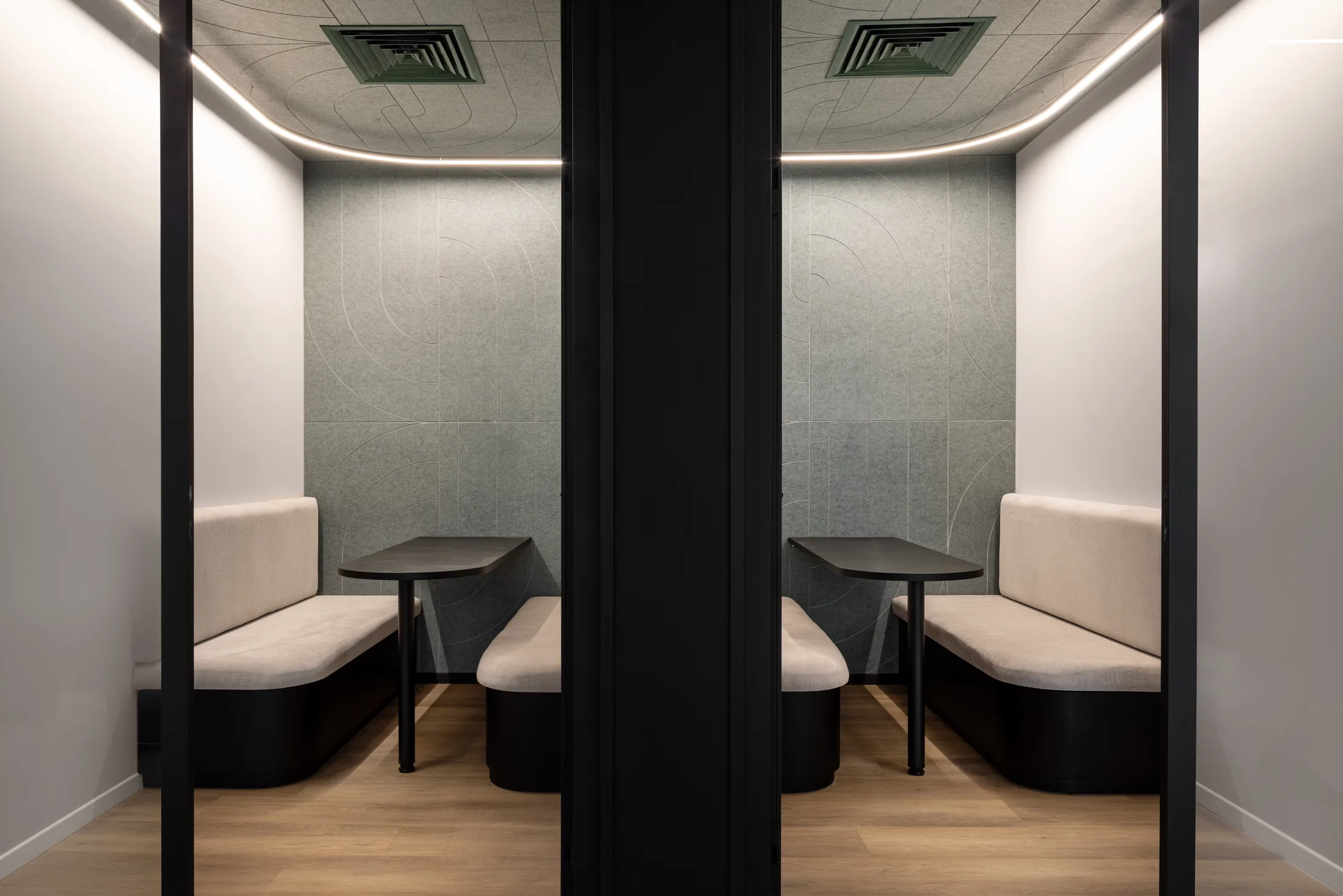 A pair of upholstered focus booths with cove lighting