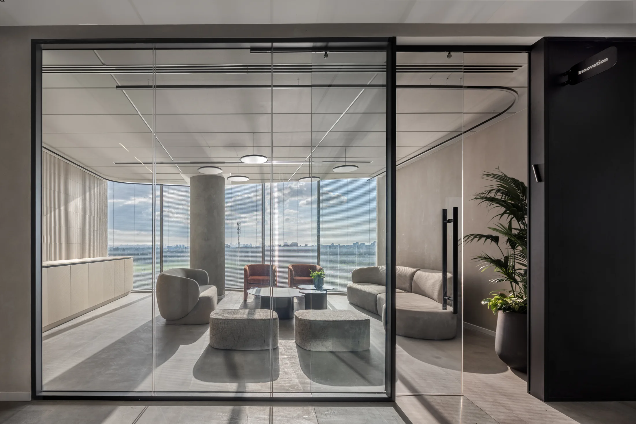 A glazed lounge room with soft seating and a city view