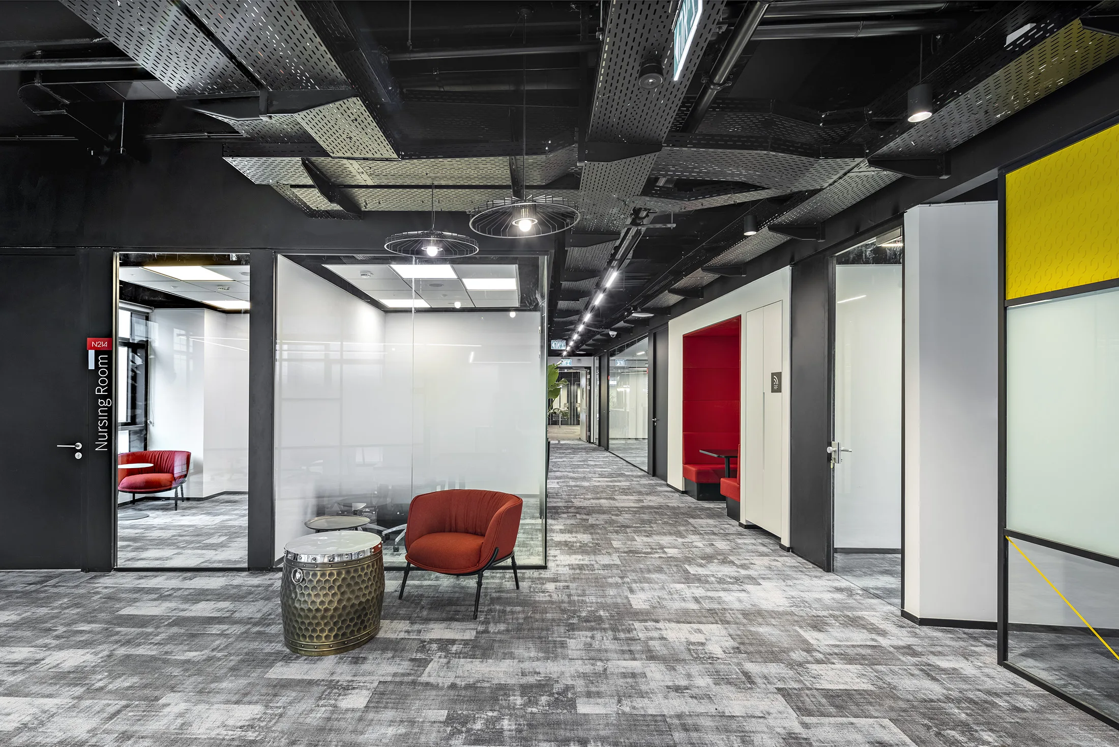 A lounge with a red armchair and pendant lights beside an exposed ceiling