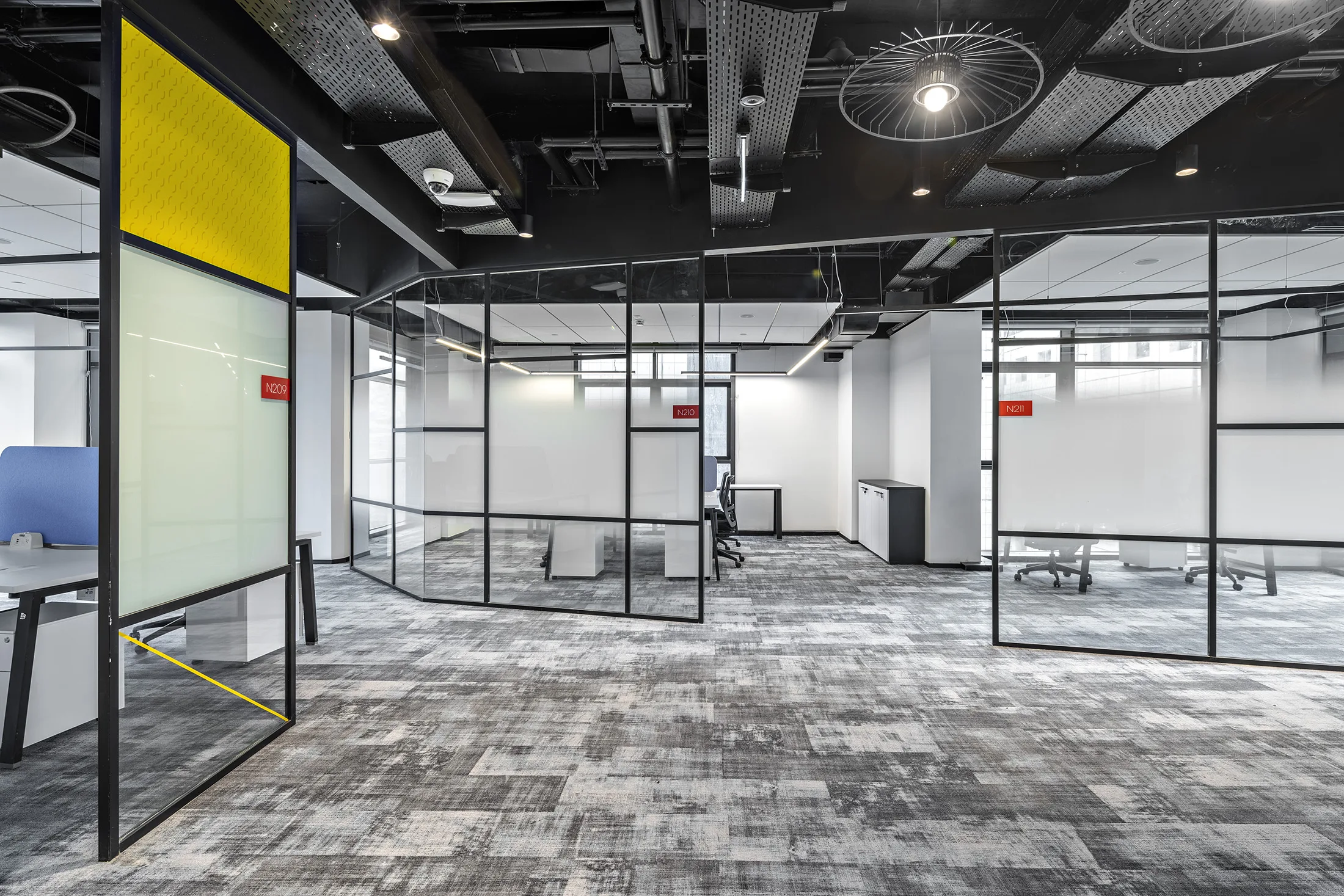 Glazed office pods in an open space with an exposed services ceiling