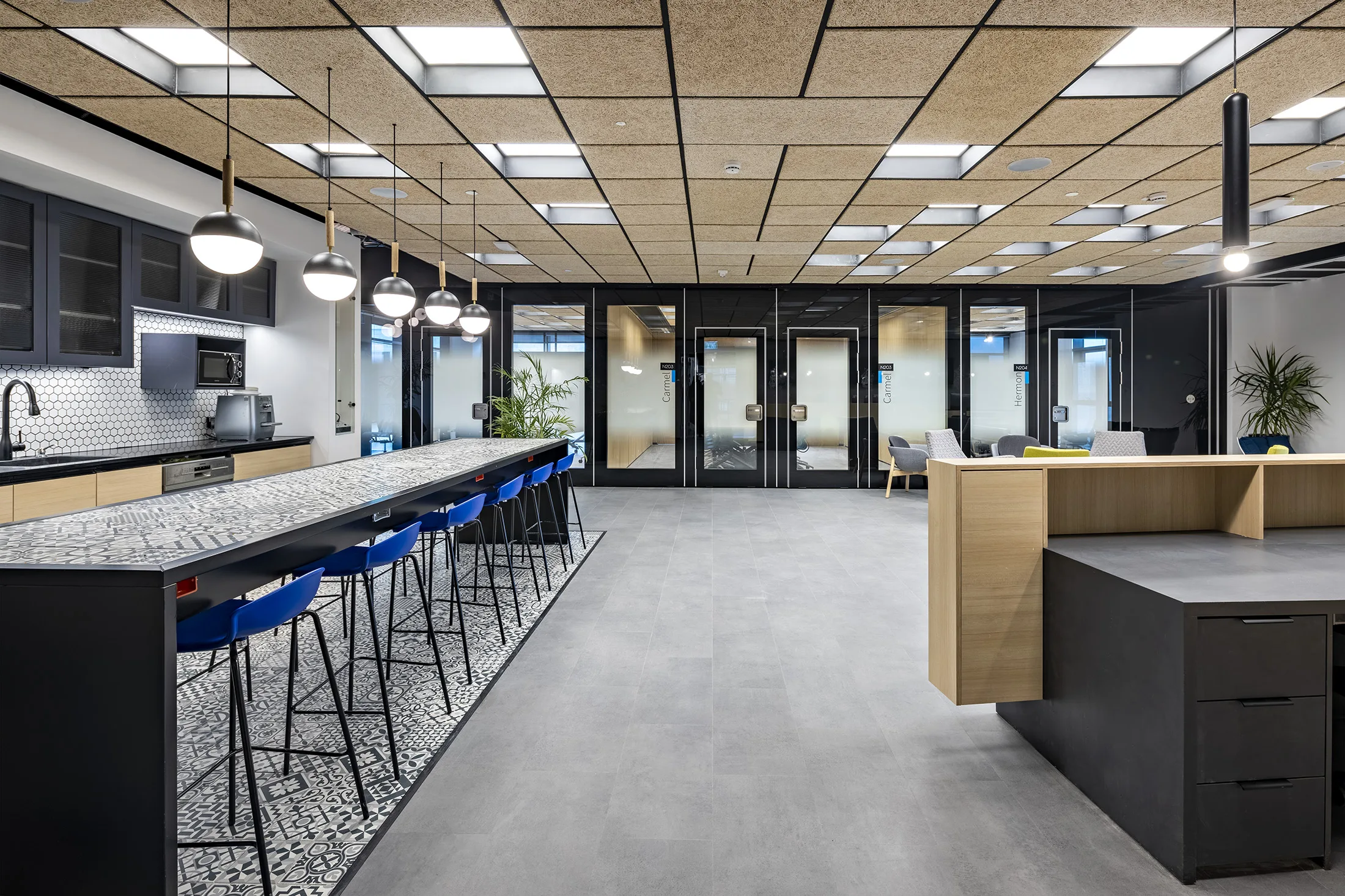 A kitchen island with a row of pendant lights under a lit wood-grid ceiling