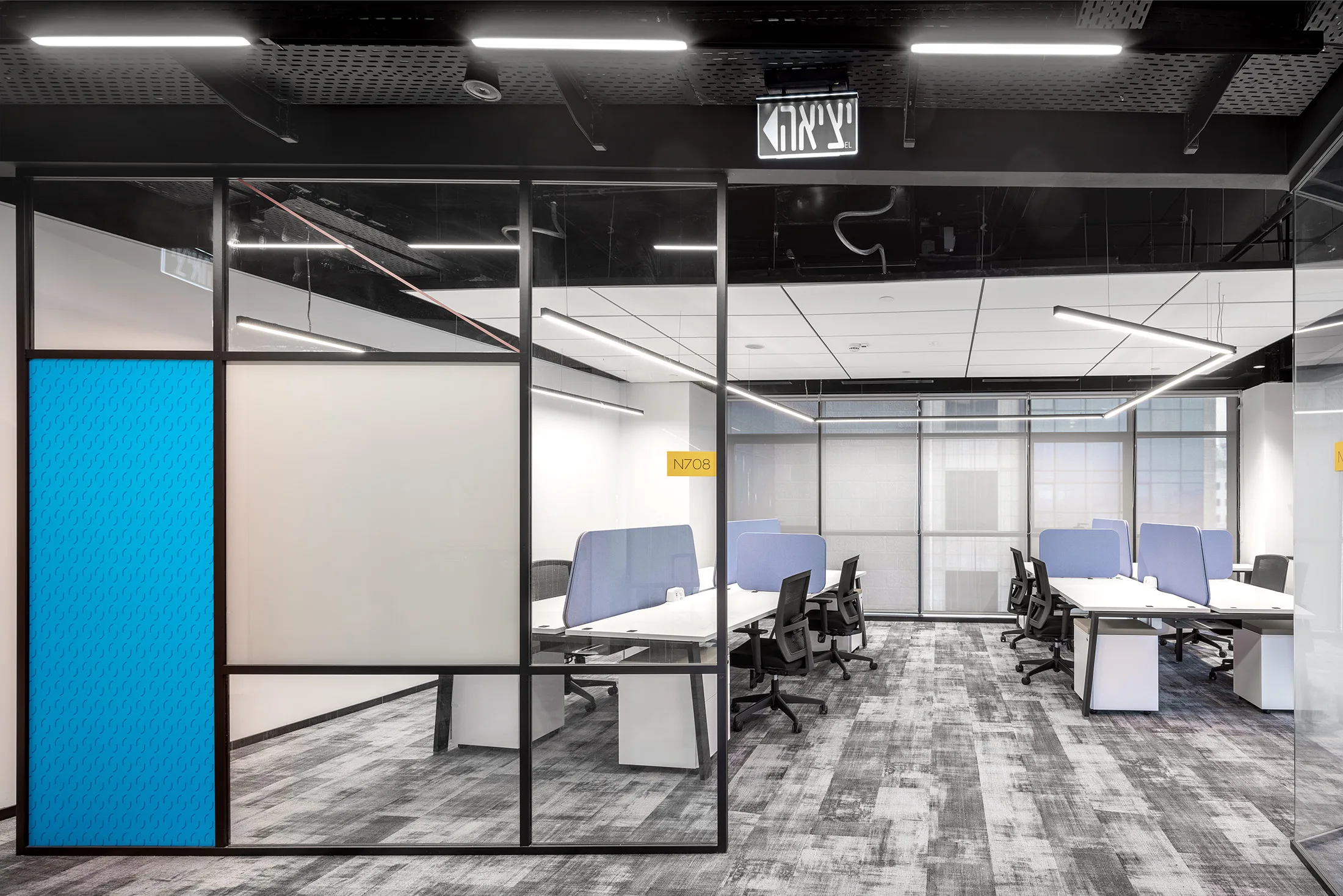 Open workstations with suspended light lines and a colored glass partition