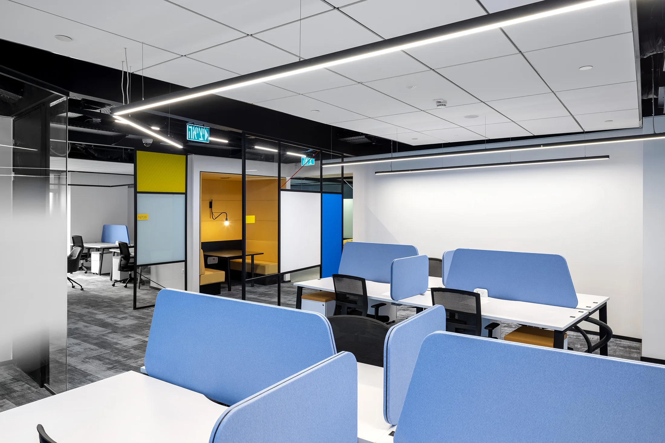 Workstations with blue acoustic screens and a suspended light line