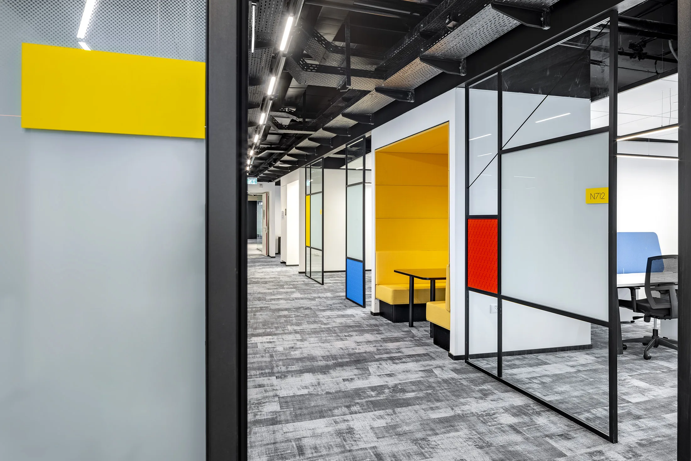 A glazed corridor with color accents and an acoustic seating booth