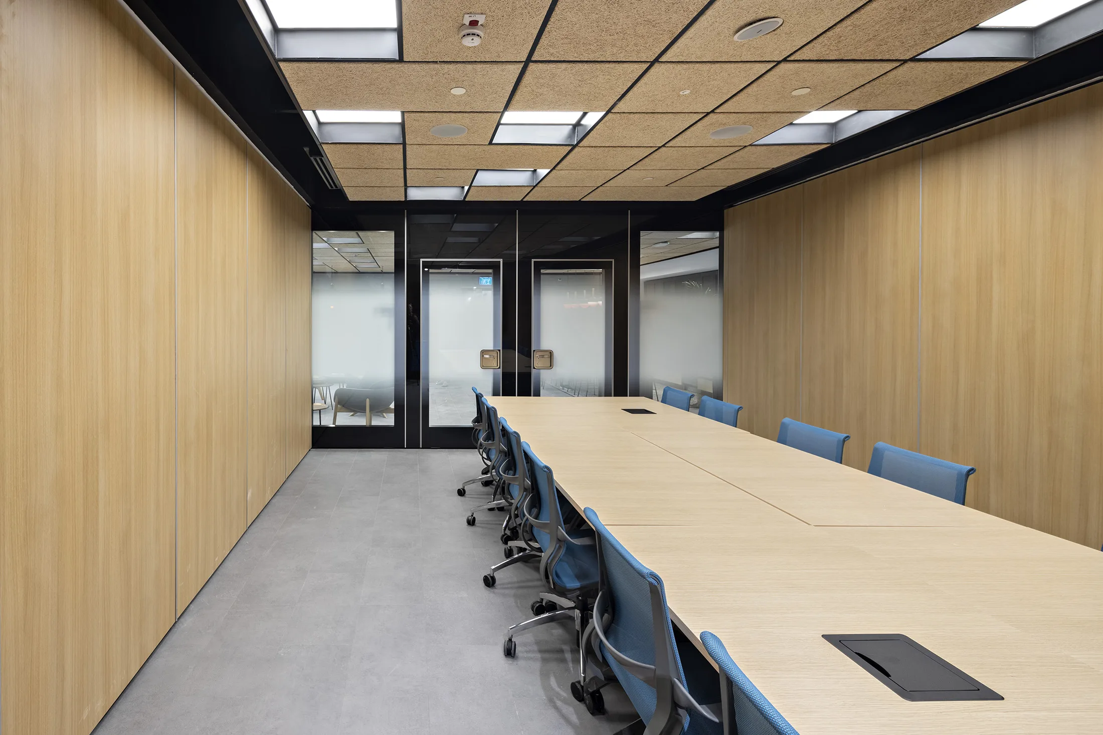A wood-clad boardroom with a lit grid ceiling