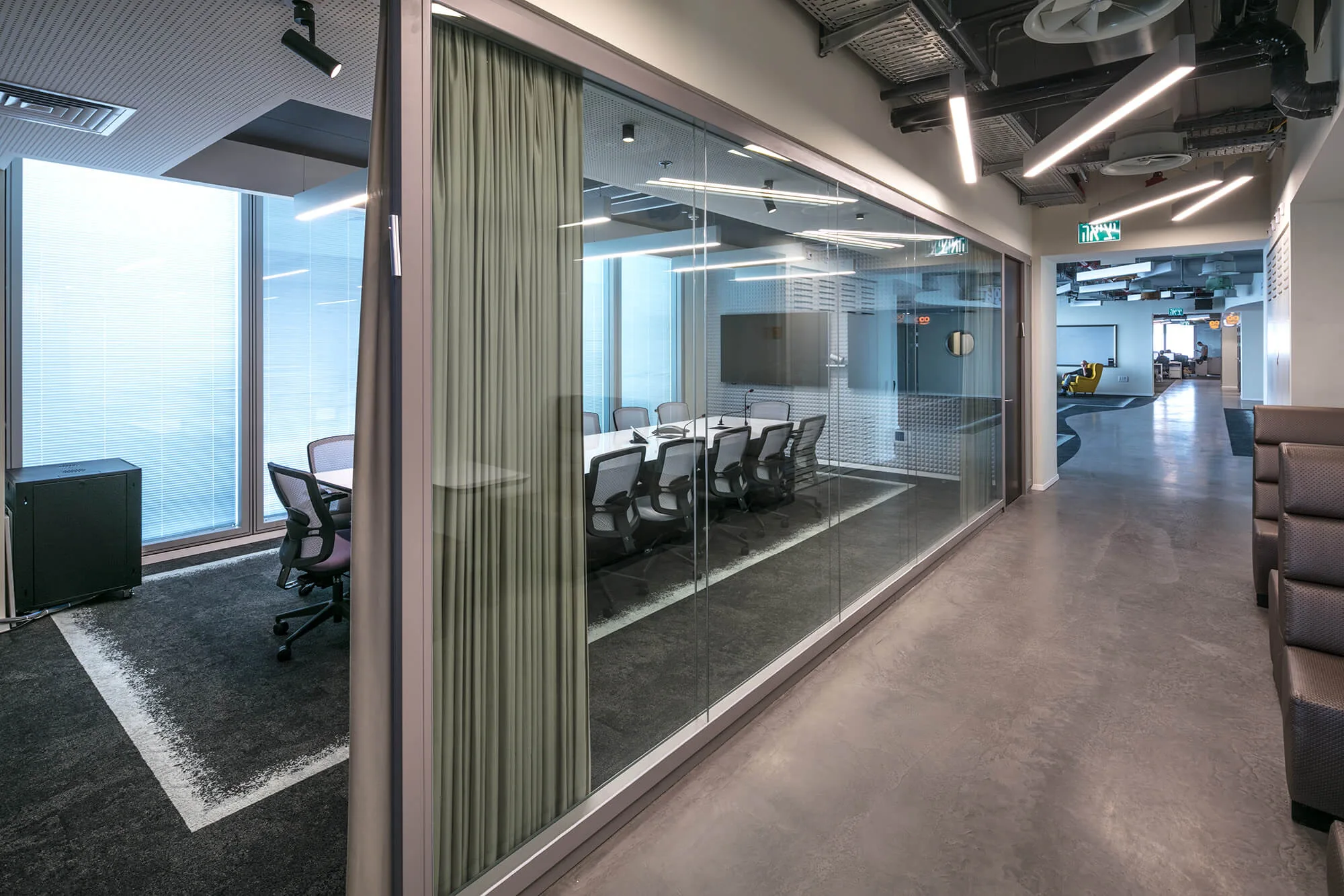 A glazed meeting room with a green curtain and linear light