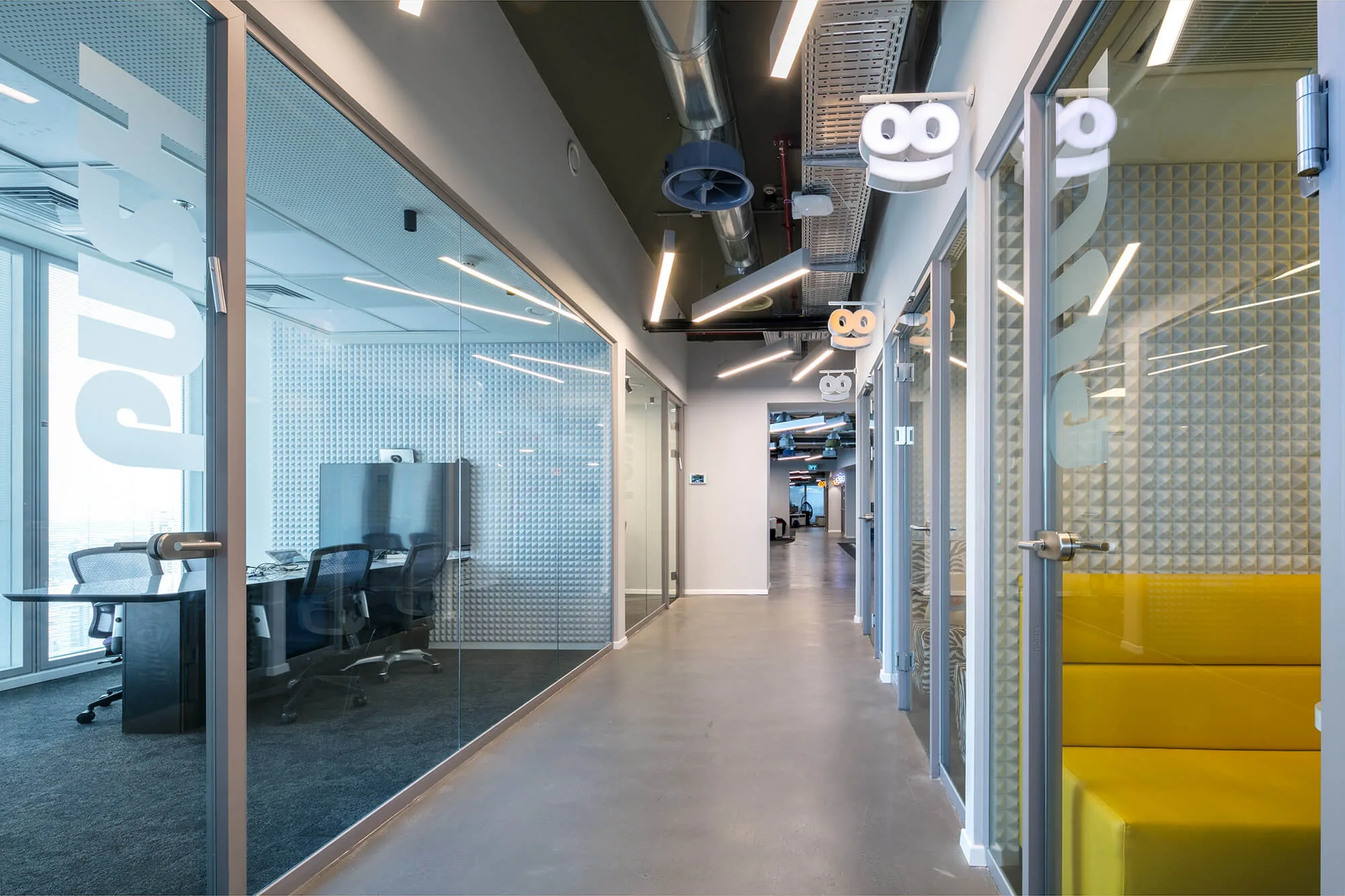 A corridor with angular linear lighting and glazed meeting rooms