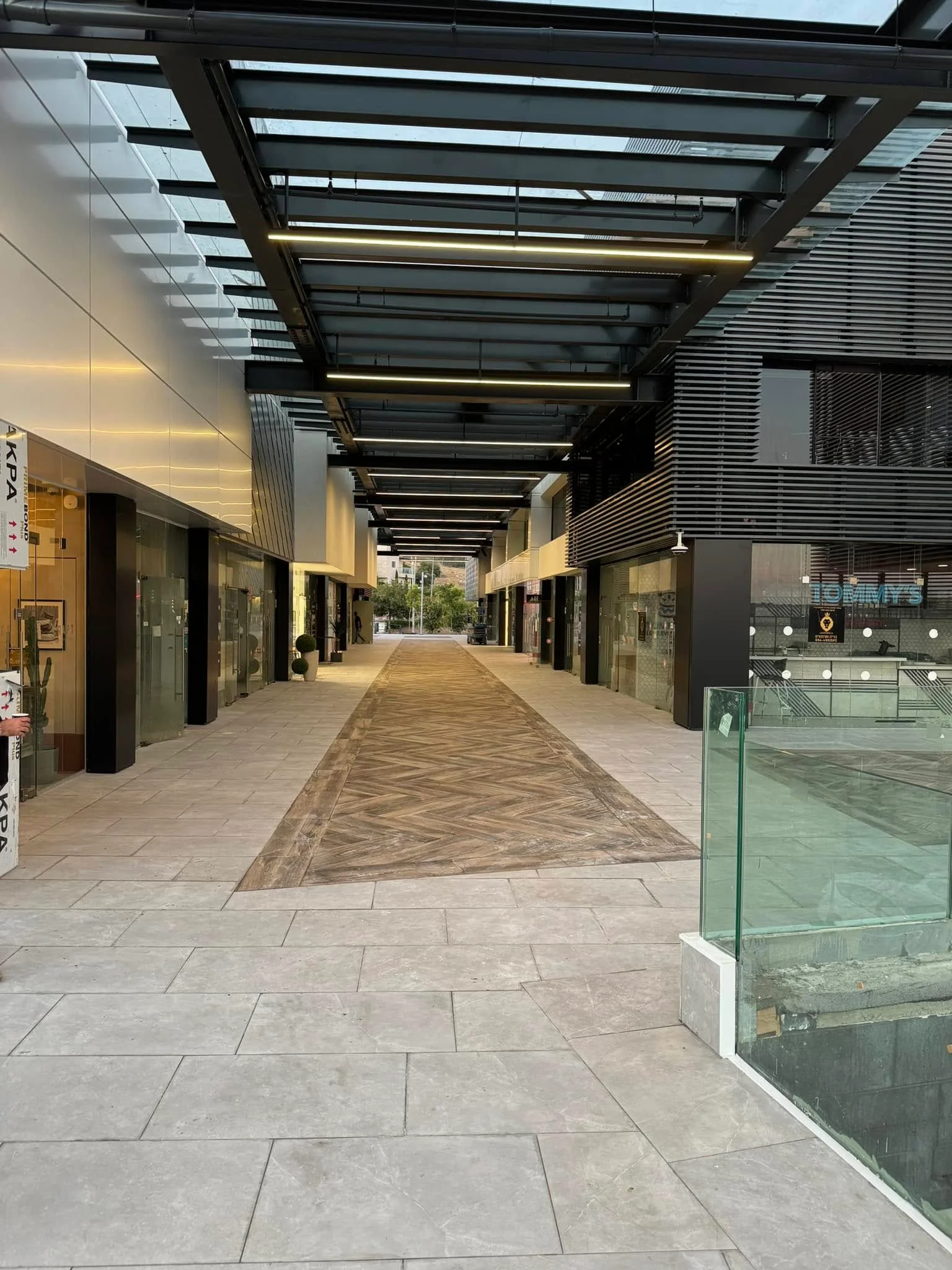 Covered pedestrian arcade with a pergola roof and storefronts