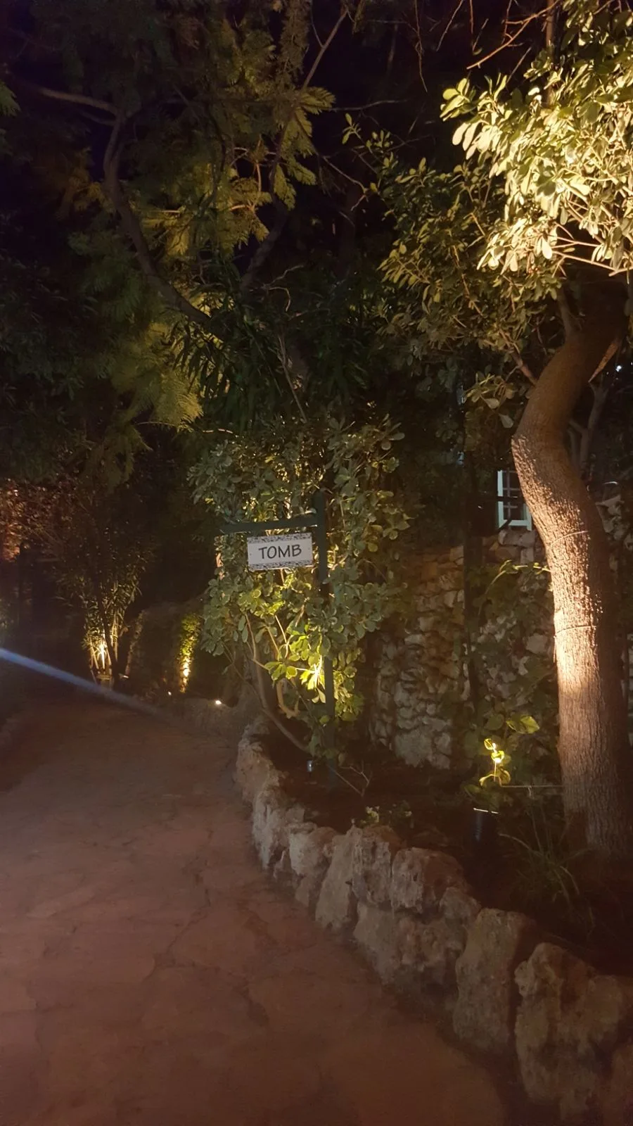 A garden path and the 'Tomb' sign under soft lighting