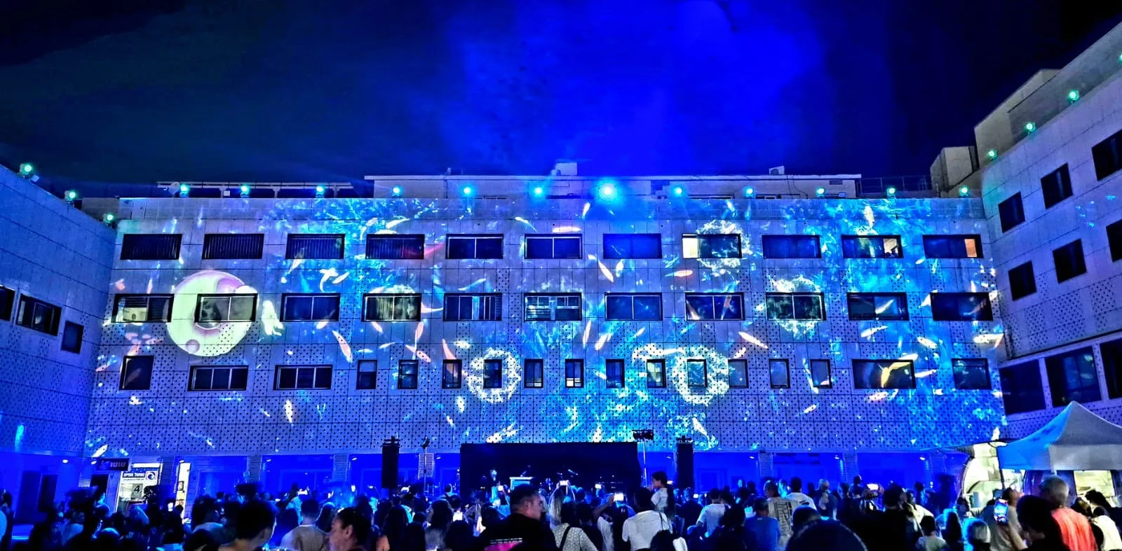 The lit facade and a full plaza of spectators