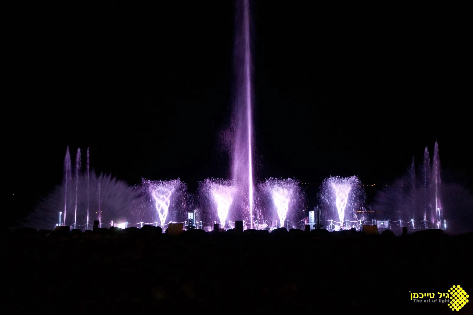 Tall purple water jets rising over the Sea of Galilee