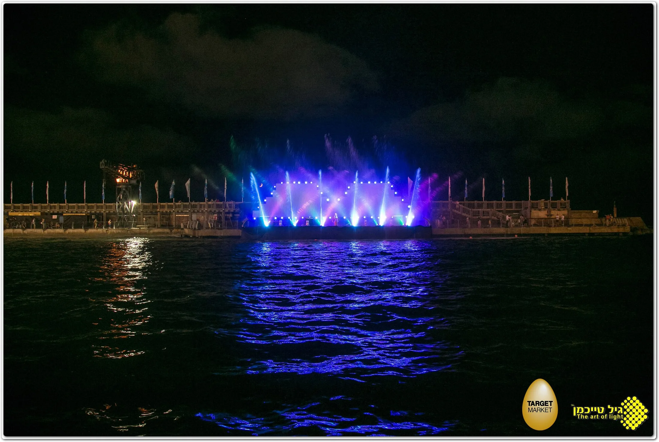 Colorful water jets and lights over the Tel Aviv Port marina at night