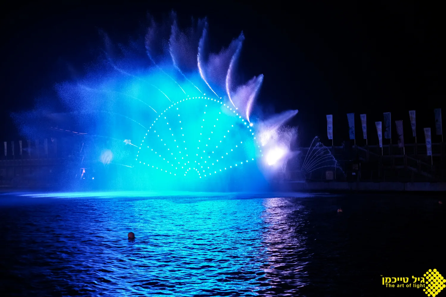 A blue water-jet fan and light array over the marina