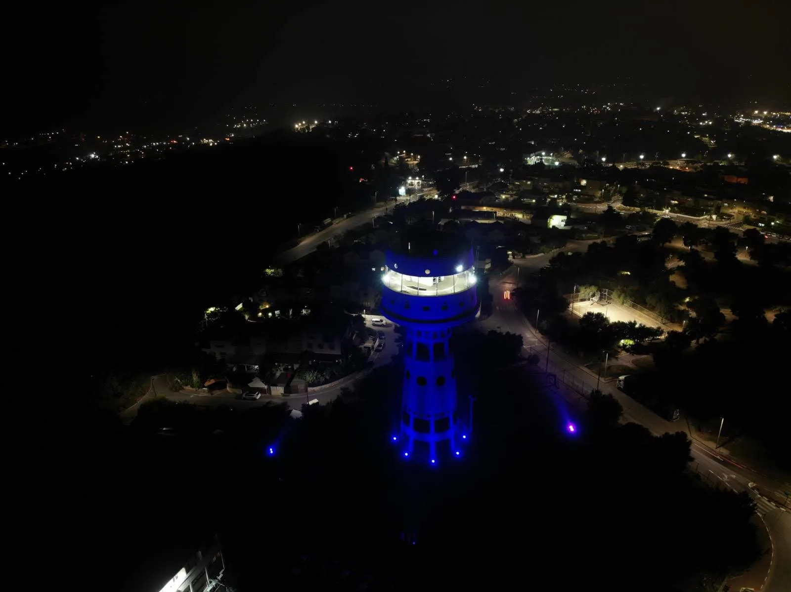 The blue-lit tower rising above the neighborhood at night