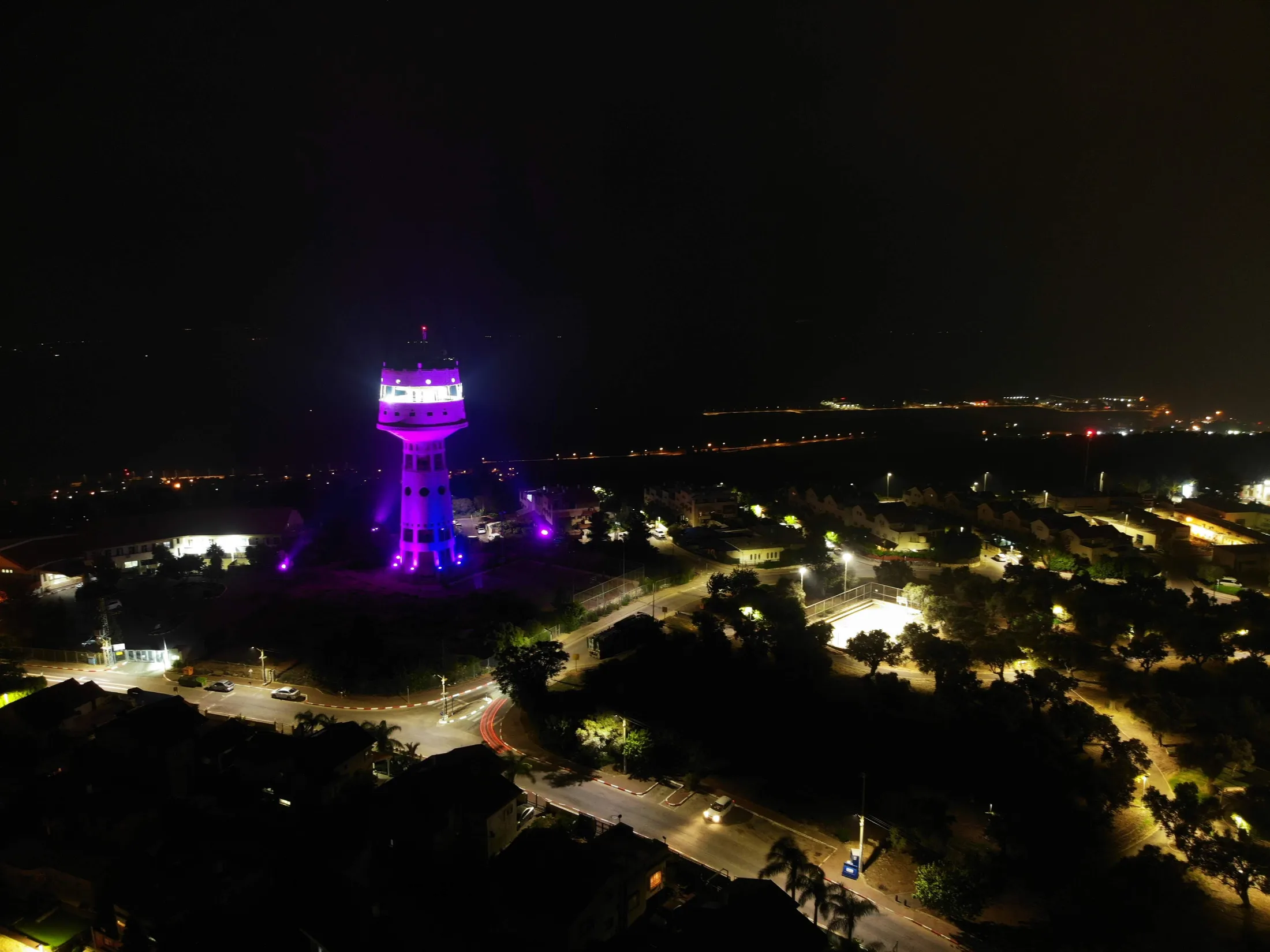 The tower lit magenta, rising above the city