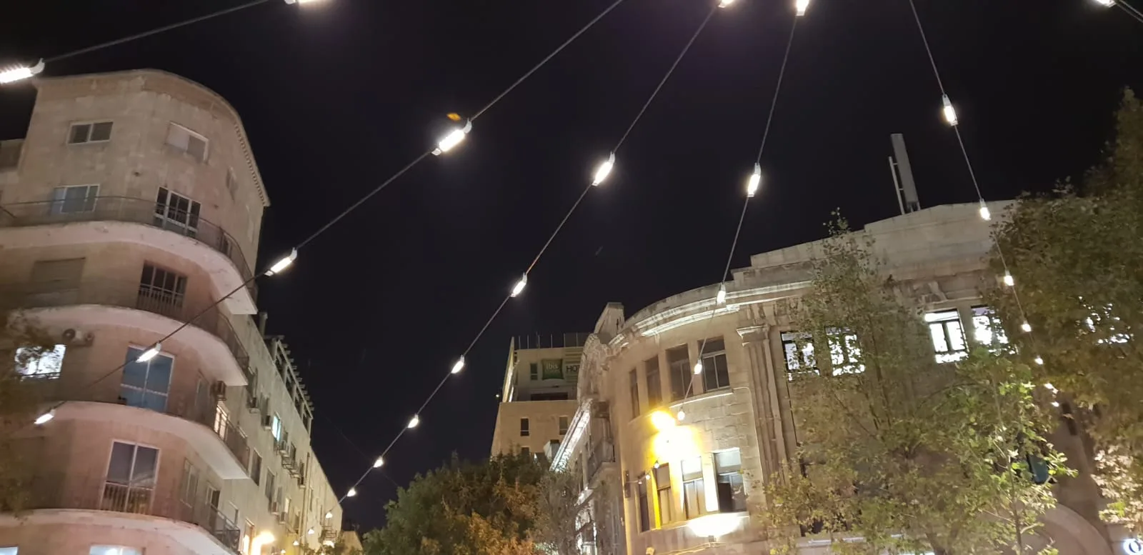 Warm festoon strings spanning the square between the historic buildings at night